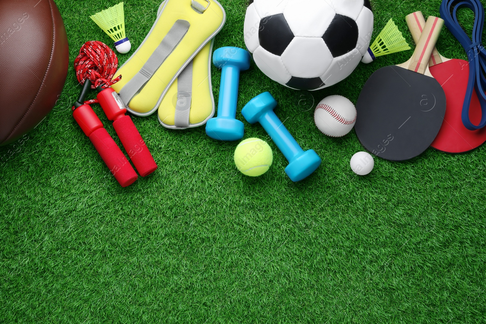 Photo of Set of different colorful sports equipment on green grass, flat lay. Space for text