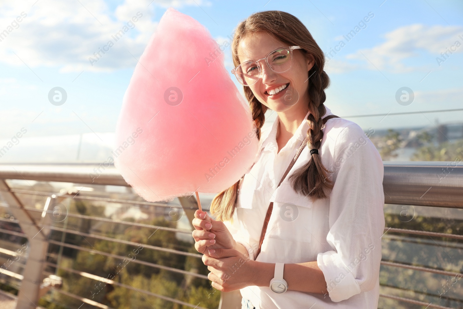 Photo of Young woman with cotton candy outdoors on sunny day