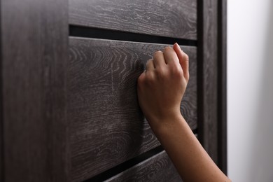 Photo of Woman knocking on door indoors, closeup view