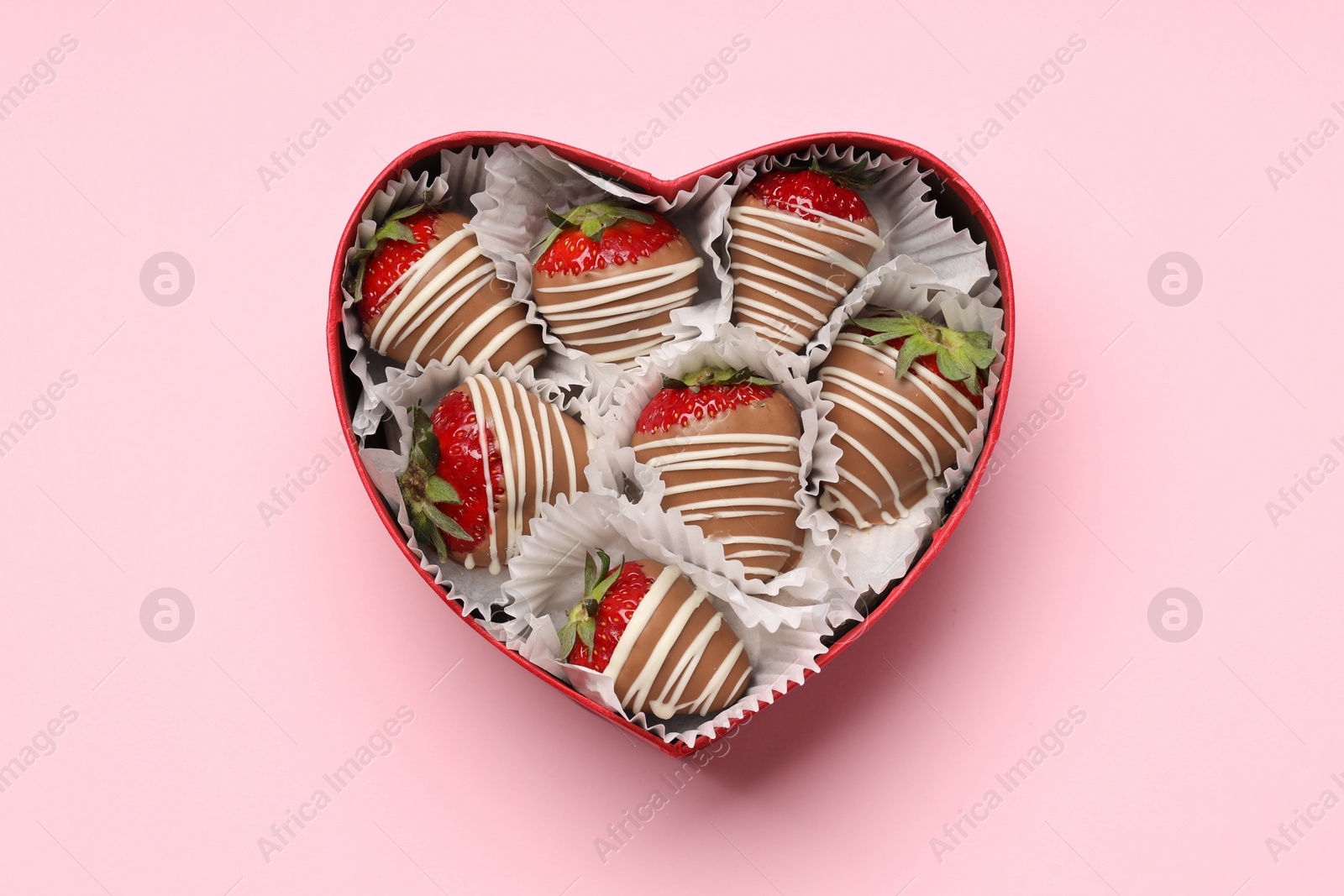 Photo of Heart shaped box with delicious chocolate covered strawberries on pink background, top view