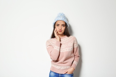 Photo of Young woman in warm sweater and knitted hat on white background. Celebrating Christmas