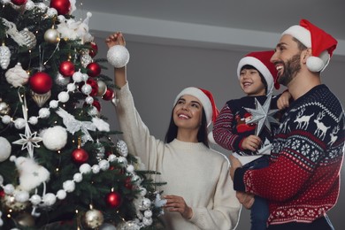 Happy family decorating Christmas tree together at home