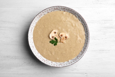 Photo of Bowl of fresh homemade mushroom soup on wooden background, top view