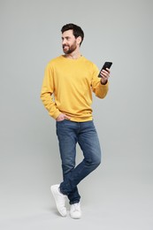 Photo of Smiling man with smartphone on grey background