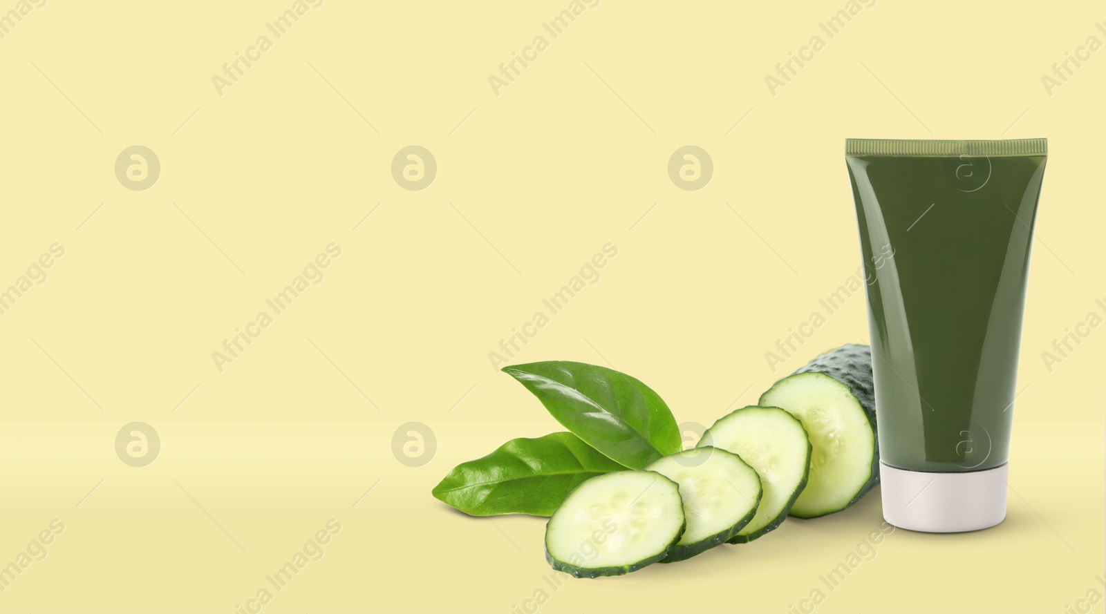 Image of Makeup remover, fresh cucumber and green leaves on yellow background. Space for text 