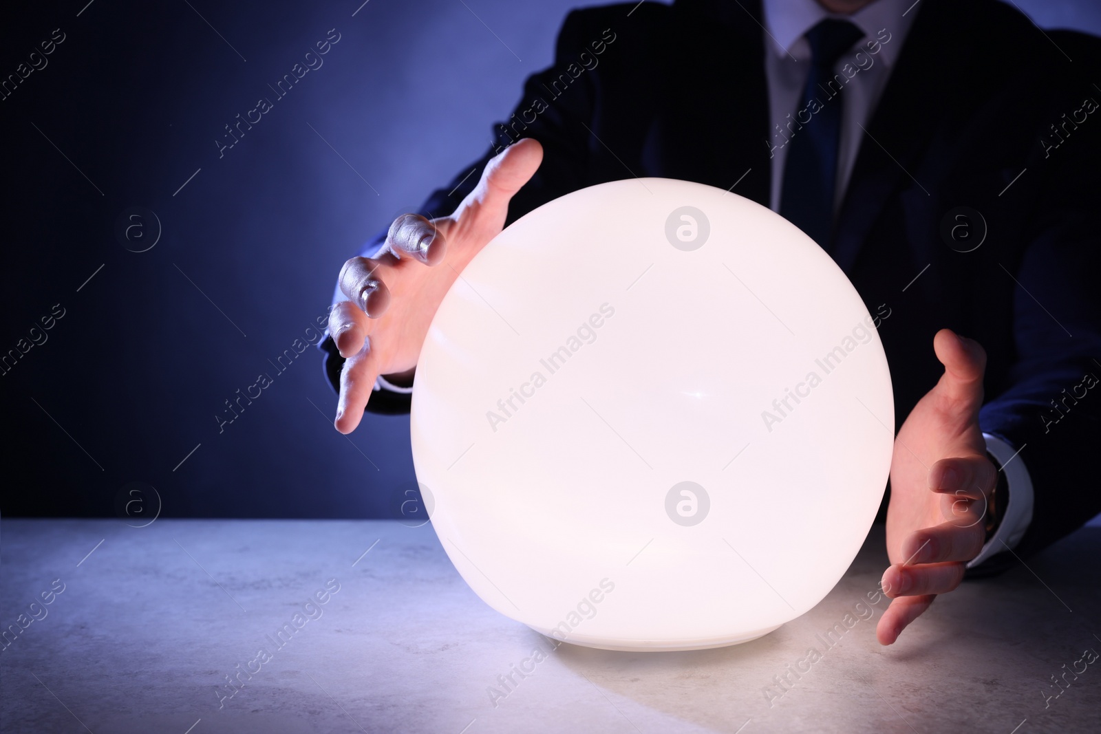 Photo of Businessman using glowing crystal ball to predict future at table, closeup. Fortune telling