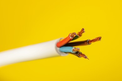 Electrical wires on yellow background, closeup view