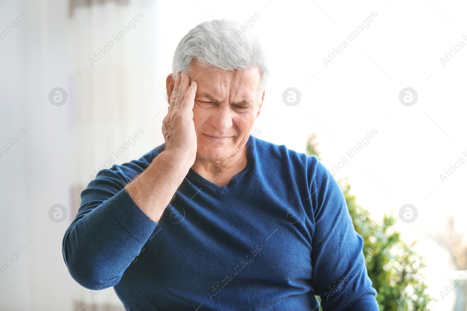 Photo of Mature man suffering from headache at home