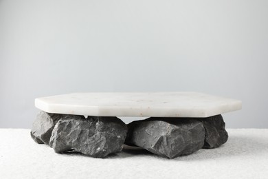 Photo of Presentation for product. Marble podium and stones on grey background. Space for text