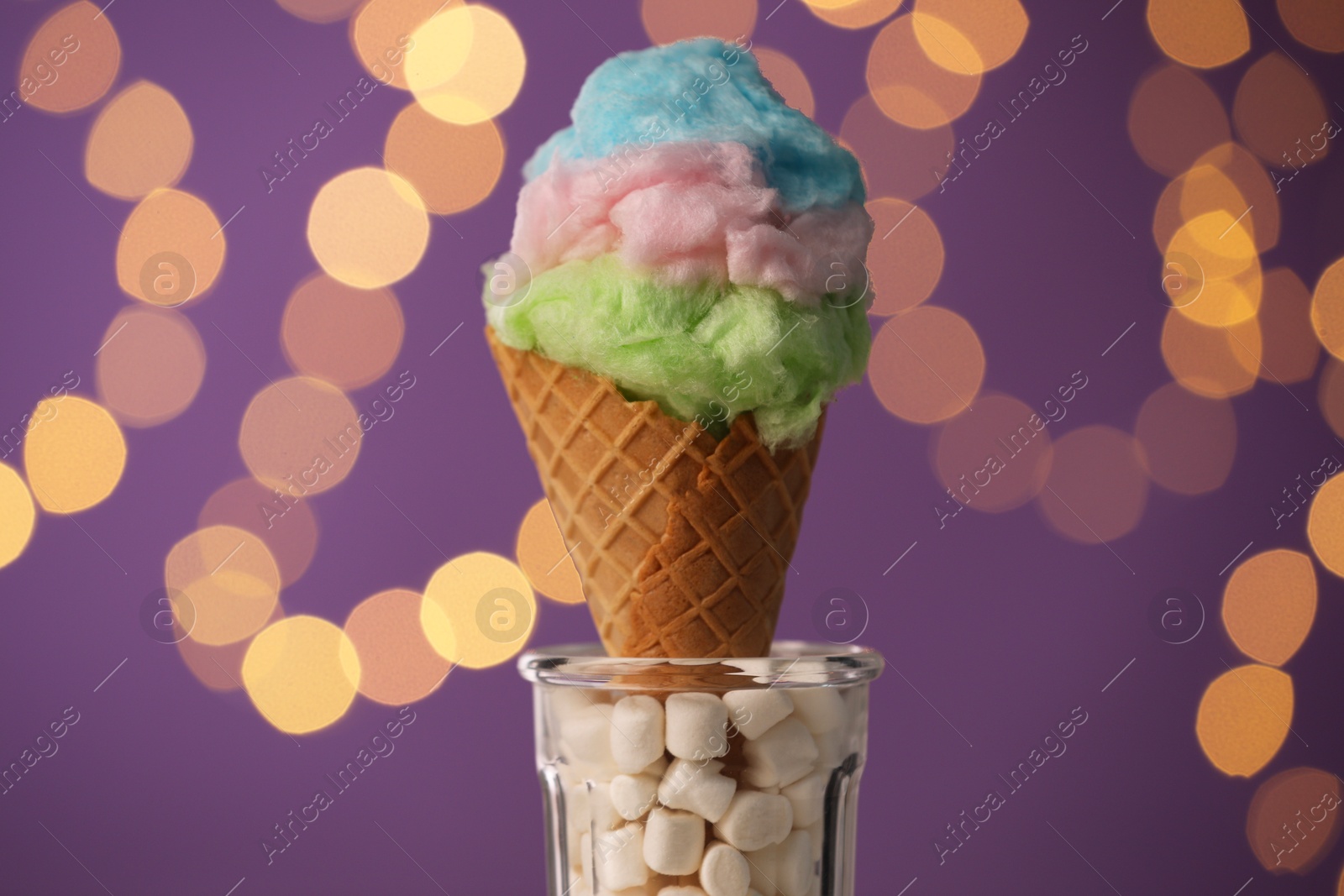 Photo of Sweet cotton candy in waffle cone against blurred lights, closeup