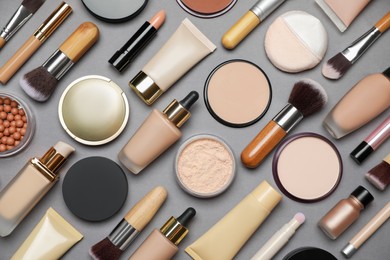 Face powders and other makeup products on grey background, flat lay