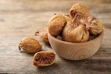 Photo of Bowl and tasty dried figs on wooden table. Space for text