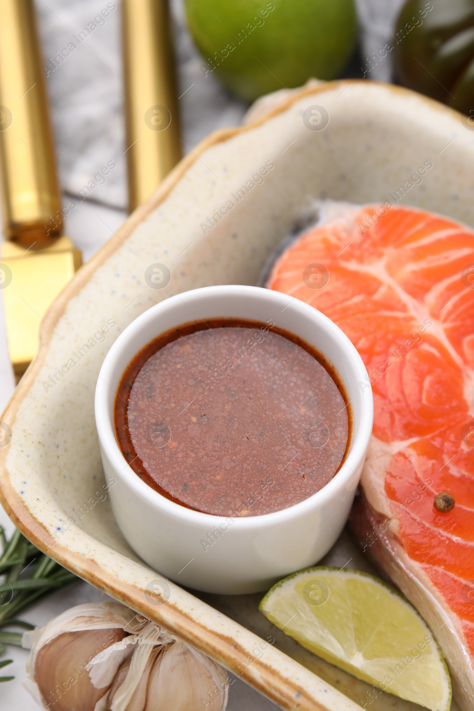 Photo of Fresh marinade, fish and lime in baking dish on table, closeup