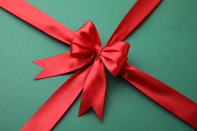Photo of Red satin ribbon with bow on green background