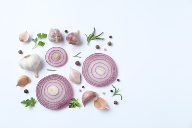 Fresh garlic, onion rings and spices on white table, flat lay. Space for text