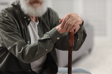 Photo of Senior man with walking cane indoors, closeup