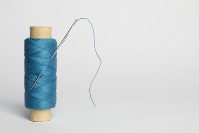 Photo of Light blue sewing thread with needle on white background