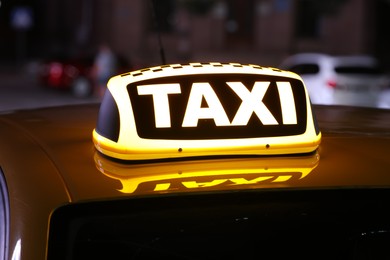 Photo of Taxi car with yellow sign on city street at night, closeup