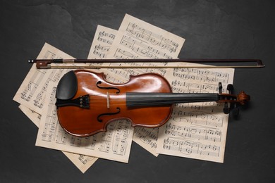 Photo of Violin, bow and music sheets on black table, top view