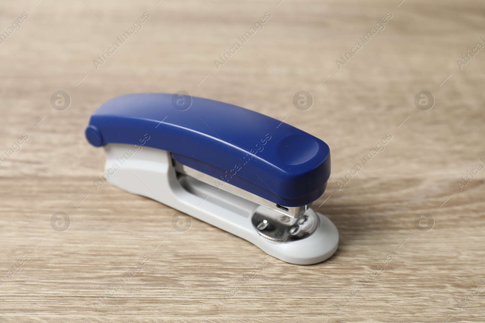 Photo of One bright stapler on wooden table, closeup