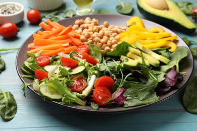 Balanced diet and vegetarian foods. Plate with different delicious products on light blue wooden table, closeup