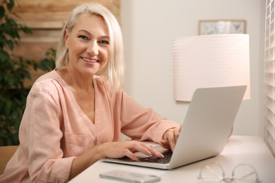 Beautiful mature woman working with laptop at home