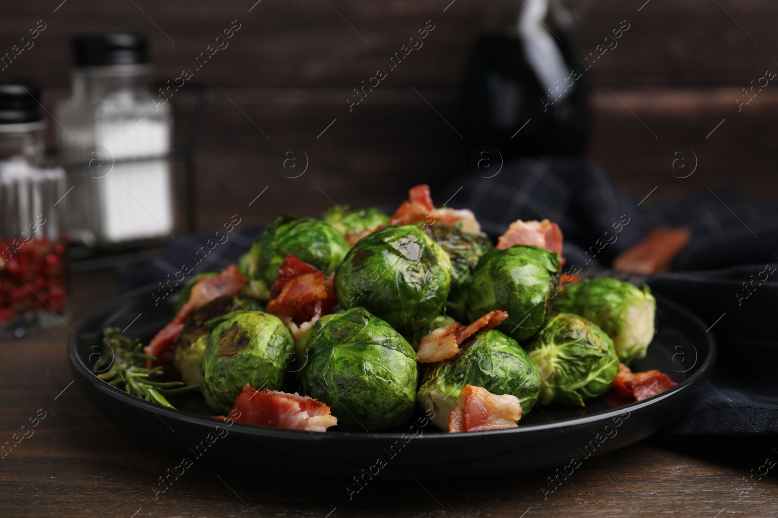 Photo of Delicious roasted Brussels sprouts and bacon on wooden table, closeup