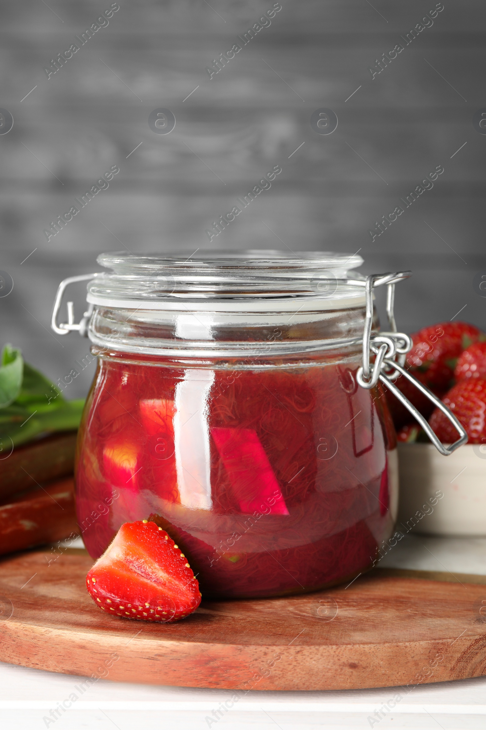 Photo of Jar of tasty rhubarb jam and strawberry on white table