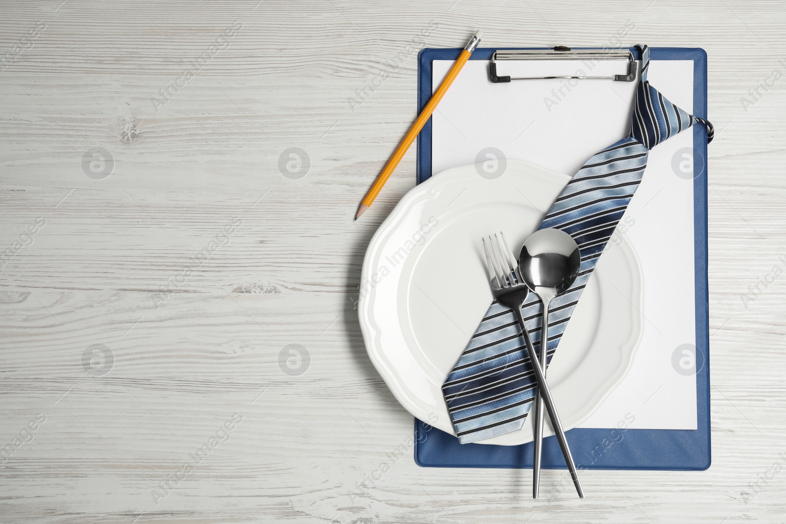 Photo of Plate with cutlery, tie and clipboard on wooden table, top view and space for text. Business lunch concept