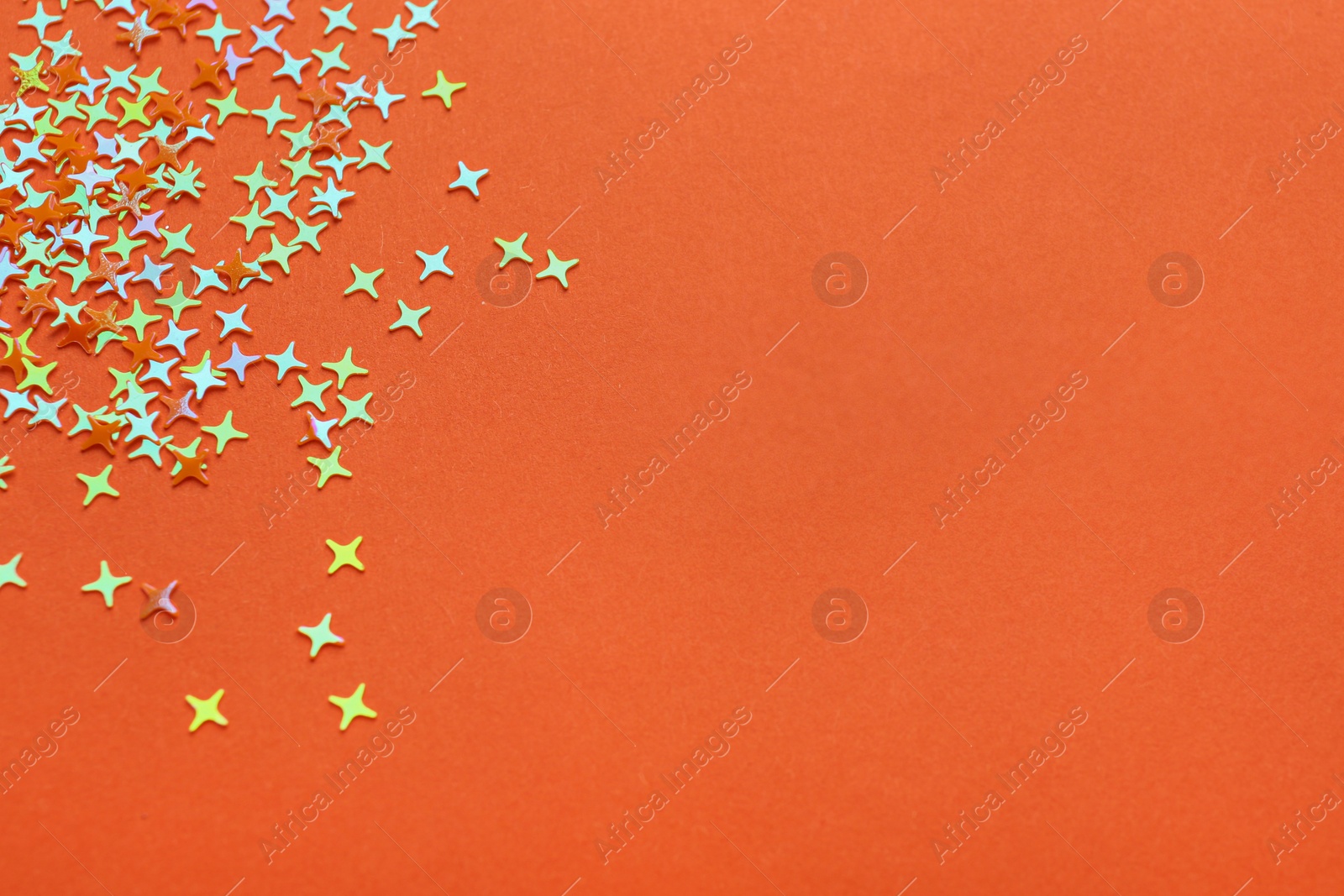 Photo of Shiny bright glitter on orange background. Space for text