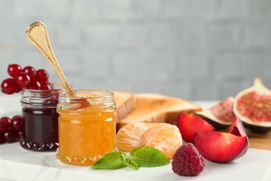 Photo of Jars with different sweet jams and ingredients on white board. Space for text