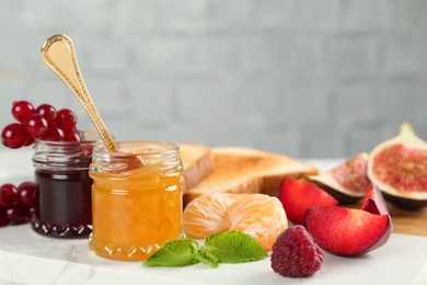 Jars with different sweet jams and ingredients on white board. Space for text