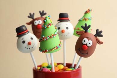 Photo of Delicious Christmas themed cake pops on beige background, closeup
