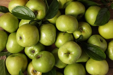 Photo of Fresh ripe green apples with leaves as background, top view