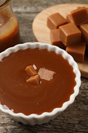 Tasty salted caramel and candies on wooden table, closeup