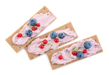 Photo of Tasty cracker sandwiches with cream cheese, blueberries, red currants and thyme on white background, top view