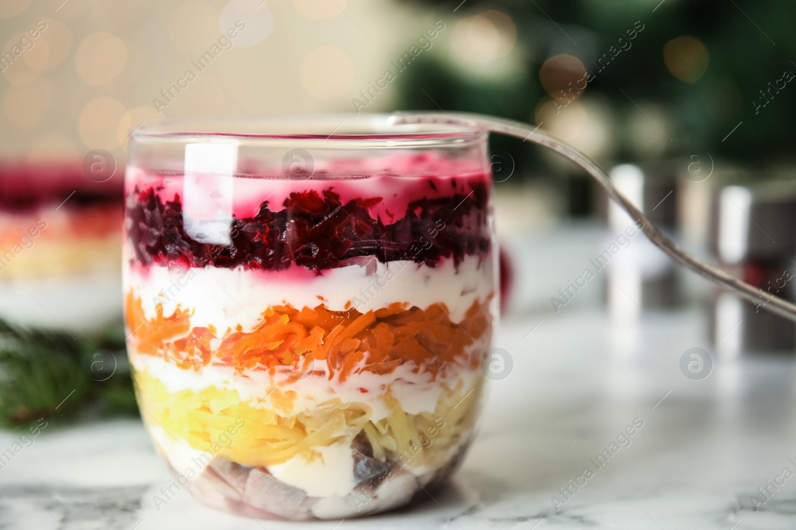 Photo of Herring under fur coat served on white marble table. Traditional russian salad