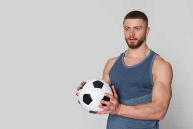 Photo of Athletic young man with soccer ball on light grey background. Space for text