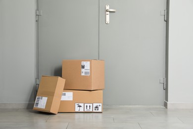 Photo of Cardboard boxes on floor near entrance. Parcel delivery service