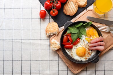 Photo of Delicious fried eggs with spinach, tomatoes and ham served on table, flat lay. Space for text