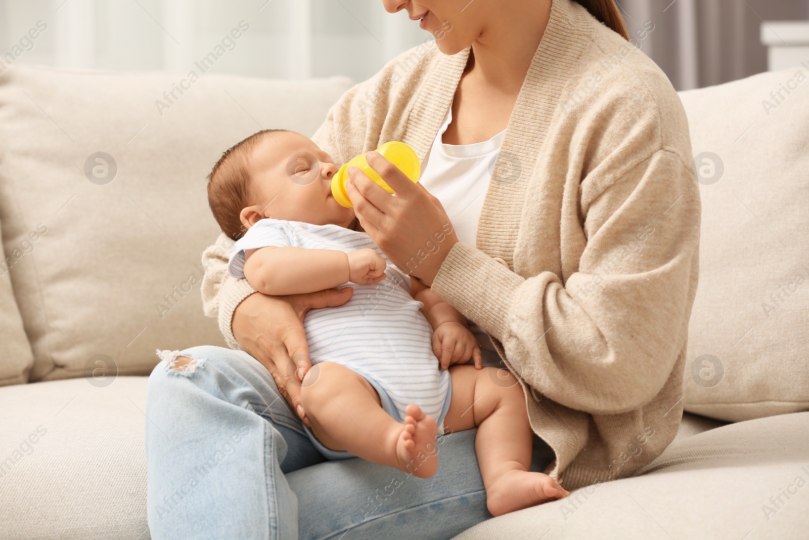 Photo of Mother feeding her cute child with infant formula indoors