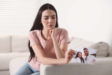 Upset woman holding torn photo at home. Divorce concept