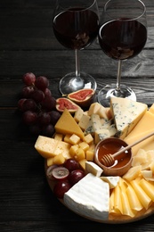 Photo of Different types of delicious cheese served on black wooden table