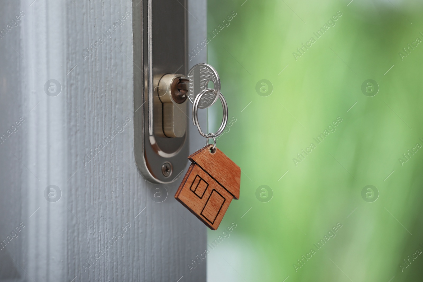 Photo of Open door with key on blurred background, closeup