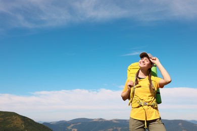 Photo of Young woman with backpack in mountains. Space for text