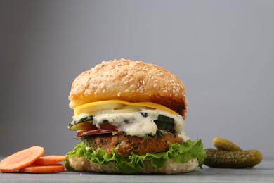 Photo of Delicious vegetarian burger and ingredients on grey wooden table