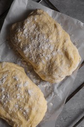 Raw dough for ciabatta and flour on grey table, top view