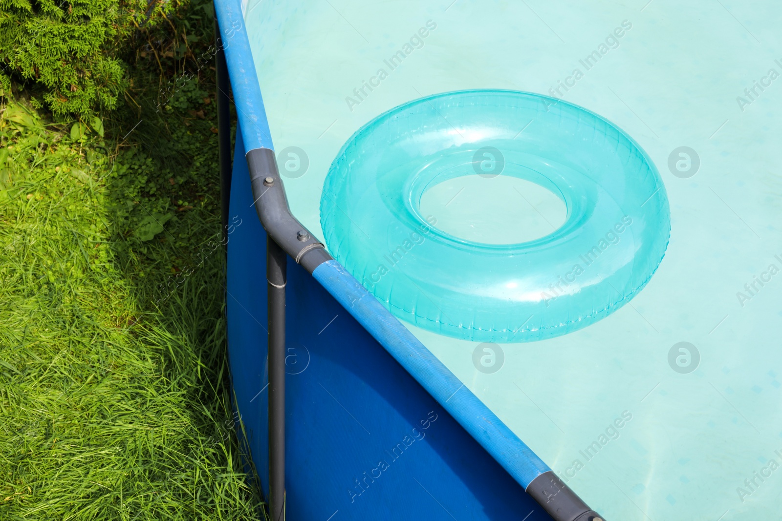 Photo of Inflatable ring floating on water in above ground swimming pool outdoors, closeup