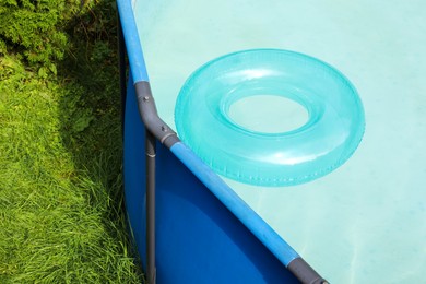 Photo of Inflatable ring floating on water in above ground swimming pool outdoors, closeup