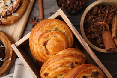 Photo of Delicious rolls with raisins and spices on table, closeup. Sweet buns